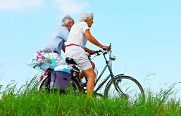 casal de idosos andando de bicicleta em um campo
