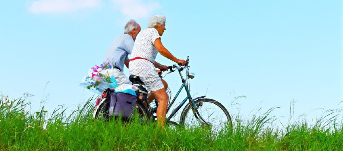 casal de idosos andando de bicicleta em um campo