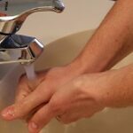 pessoa lavando as mãos em uma pia