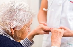 médico segurando as mãos de uma idosa