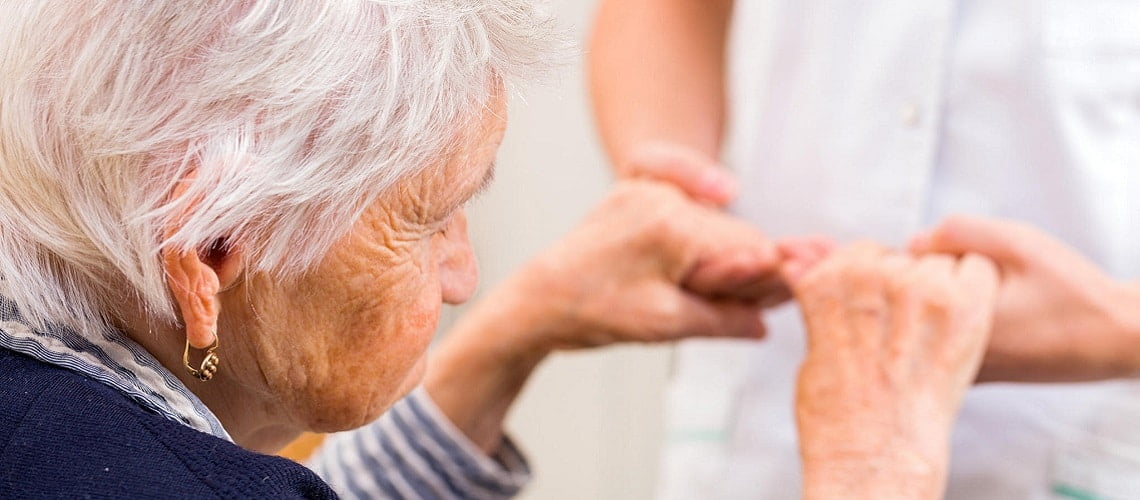 médico segurando as mãos de uma idosa