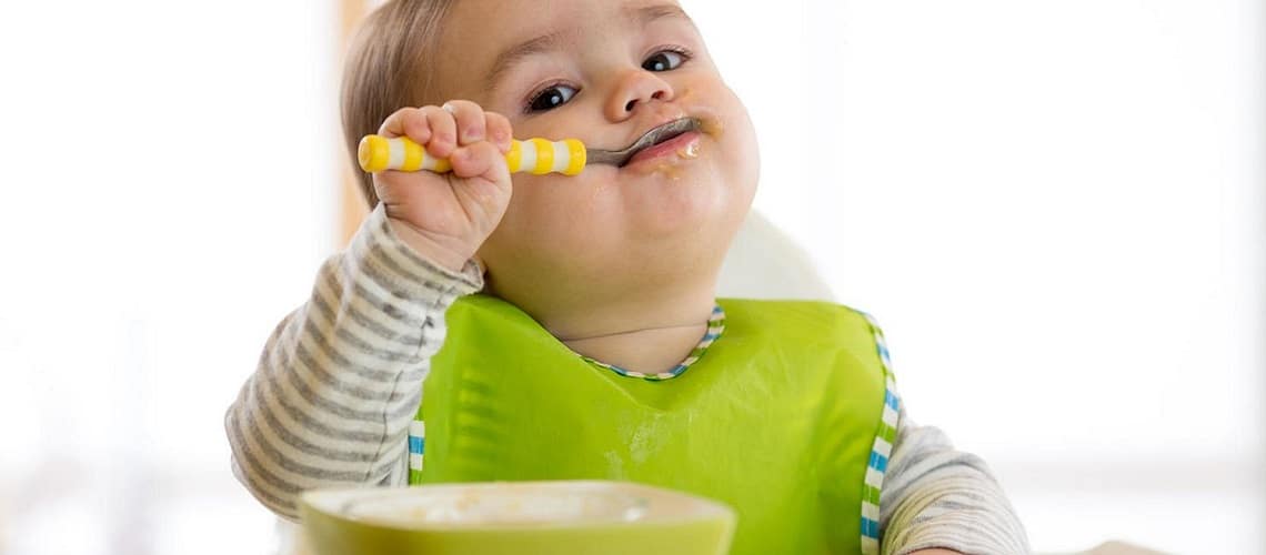 criança comendo com colher de uma tigela