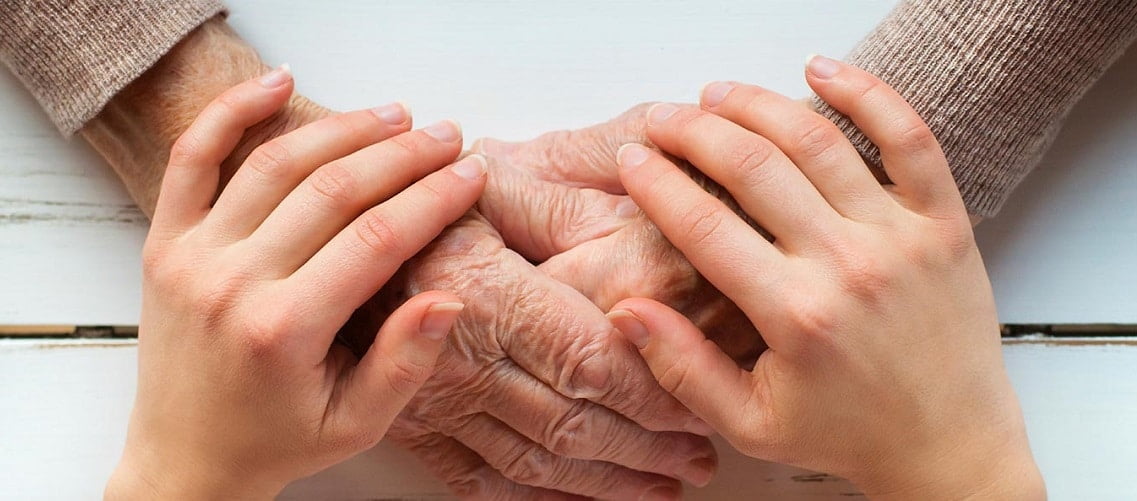 Cuidador segurando mão de idoso