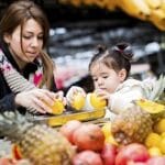mãe e filha escolhendo frutas no mercado