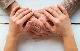 Cuidador segurando a mão de um idoso