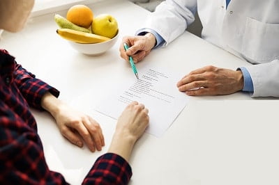 médico mostra dieta para paciente na mesa tem uma tigela com frutas