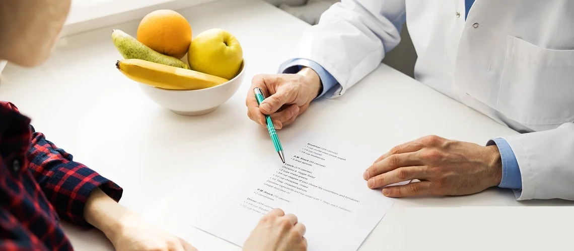 médico mostra dieta para paciente na mesa tem uma tigela com frutas