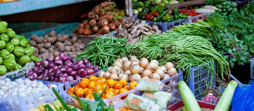 Foto de banca de feira com variedade de legumes, tubérculos e hortaliças.