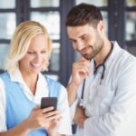 mulher e médico olham tela de celular