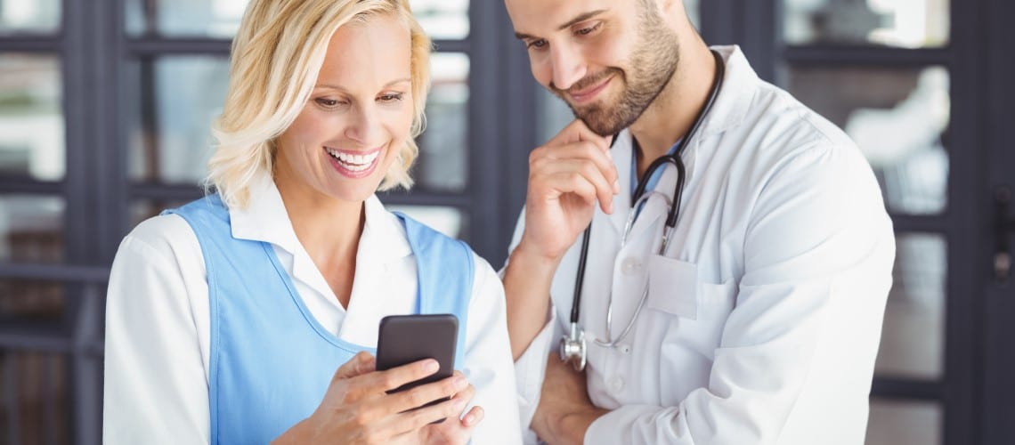 mulher e médico olham tela de celular