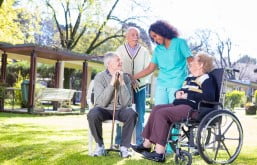 grupo de idosos com uma enfermeira em um jardim