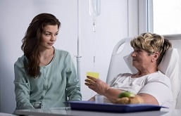 Filha ajudando a mãe a se alimentar no hospital