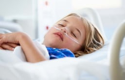Criança deitada em cama hospitalar