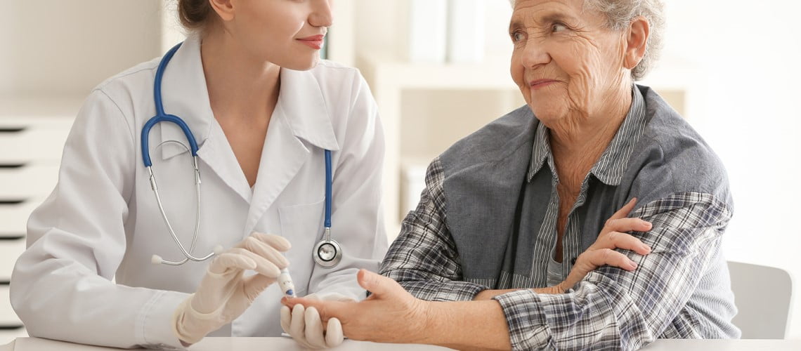 Imagem de uma médica realizando testes clínicos em uma senhora, segurando a sua mão.