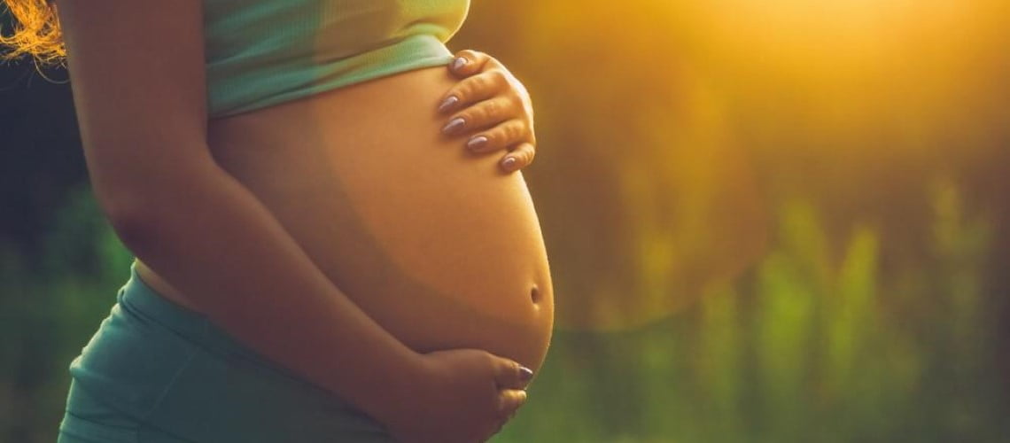 Imagem de uma mulher grávida segurando a sua barriga.