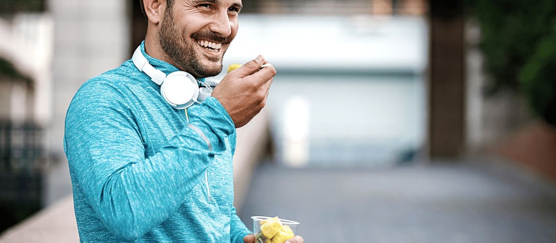 Homem praticante de atividade física comendo frutas.