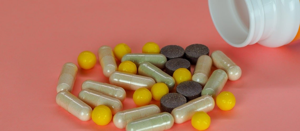 capsulas e comprimidos de remédio espalhados na mesa