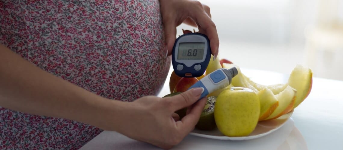 mulher medindo nível de insulina com medidor digital e prato de frutas sobre a mesa