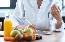 médico anotando dados de um remédio em uma mesa com de frutas