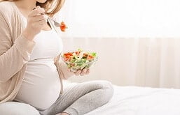 imagem de uma mulher gravida comendo verduras.