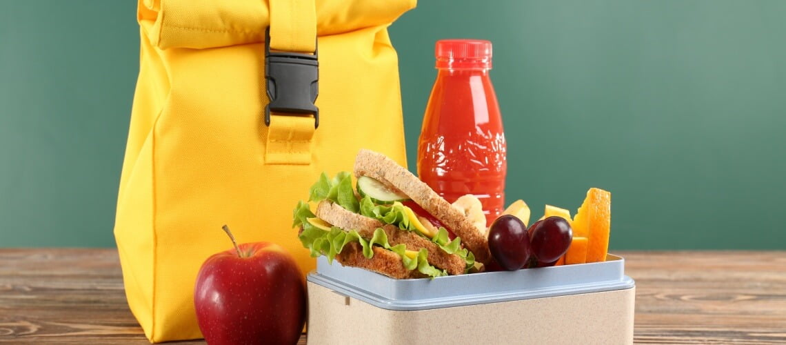 pote com sanduiches e frutas, maçã, garrafa de suco e bolsa