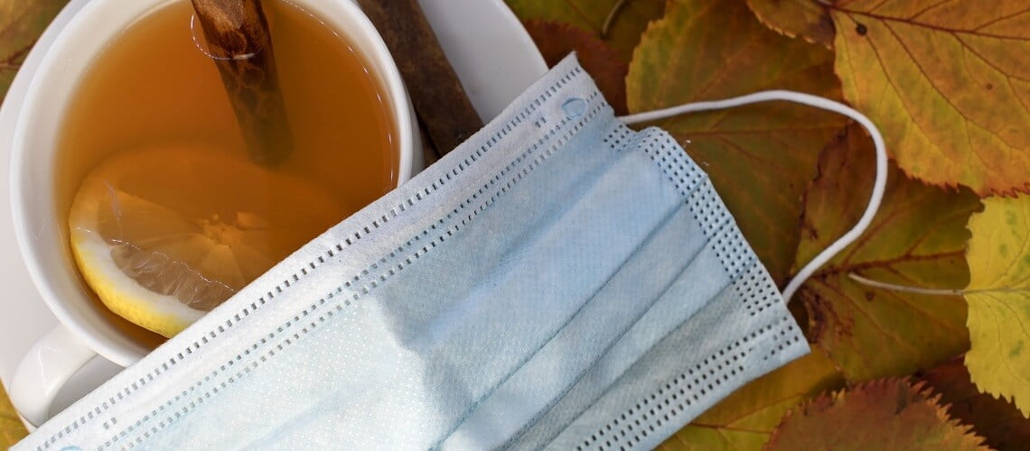 máscara de proteção facial, xícara de chá com laranja e canela
