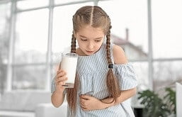 criança bebendo leite e sentindo o estômago