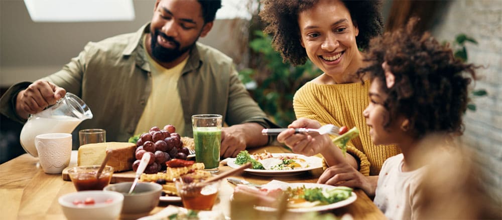 Família feliz na mesa com alimentos vegetarianos.