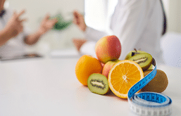 Imagem de frutas em cima da mesa com uma fita métrica.