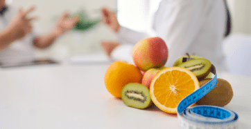 Imagem de frutas em cima da mesa com uma fita métrica.