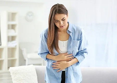 Mulher com as mãos na barriga indicando desconforto