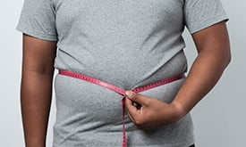 Homem medindo a circunferência da barriga com fita métrica