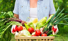 Mulher segurando cesta de verduras e legumes