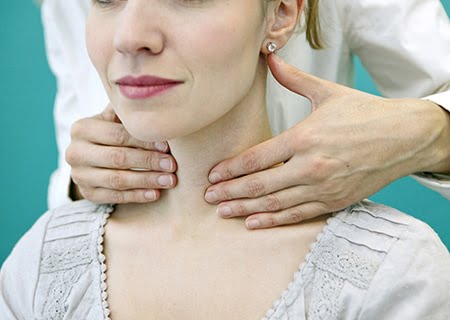 Mulher sentada e médico atrás apalpando seu pescoço para verificar a tireoide