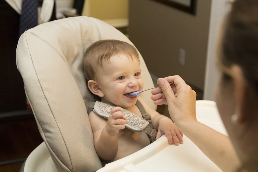 Bebê feliz recebendo comida na boca