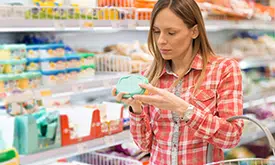 Mulher no supermercado lendo rótulo de alimento