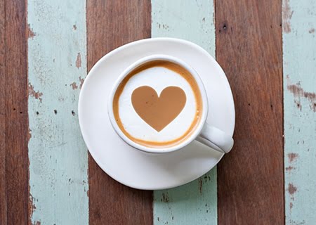 Xícara de café em cima da mesa. Bebida forma um coração.