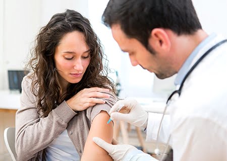Mulher recebendo aplicação de vacina de médico no braço