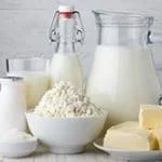 Mesa com jarra e garrafas de leite, manteiga e queijos
