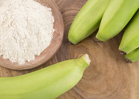 Banana verde ao lado de pote de farinha