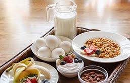 Bandeja de um café da manhã saudável: com jarra de leite, pote com ovos, prato com iogurte e frutas...