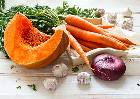 Mesa com cenouras, melão, alho e cebolas - exemplos de alimentos antioxidantes que atuam na prevenção do câncer de pele