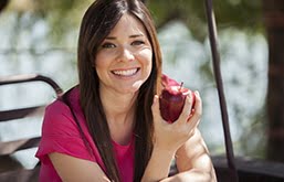 Moça sorrindo segurando maçã na mão