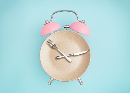 Relógio em forma de prato, com um garfo e uma faca em cima