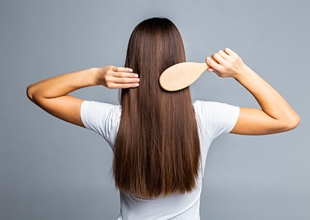 Mulher de costas penteando os cabelos com uma escova. <a href='https://br.freepik.com/fotos-vetores-gratis/mulher'>Mulher foto criado por diana.grytsku - br.freepik.com</a>