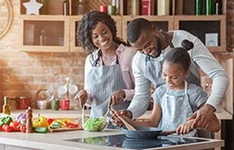 Homem, mulher e criança na cozinha cozinhando e sorrindo