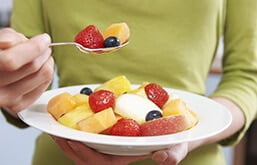 Pessoa segurando prato com frutas picadas dentro