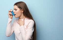 Mulher inalando bombinha de asma