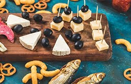 Mesa com alimentos ricos em sódio, como azeitonas, queijos, salgadinhos e peixes em conserva. Crédito da imagem: azerbaijan_stockers/Freepik.