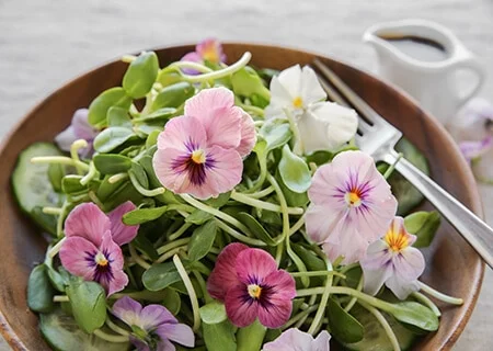 Tigela com salada de folhas, brotos e flores